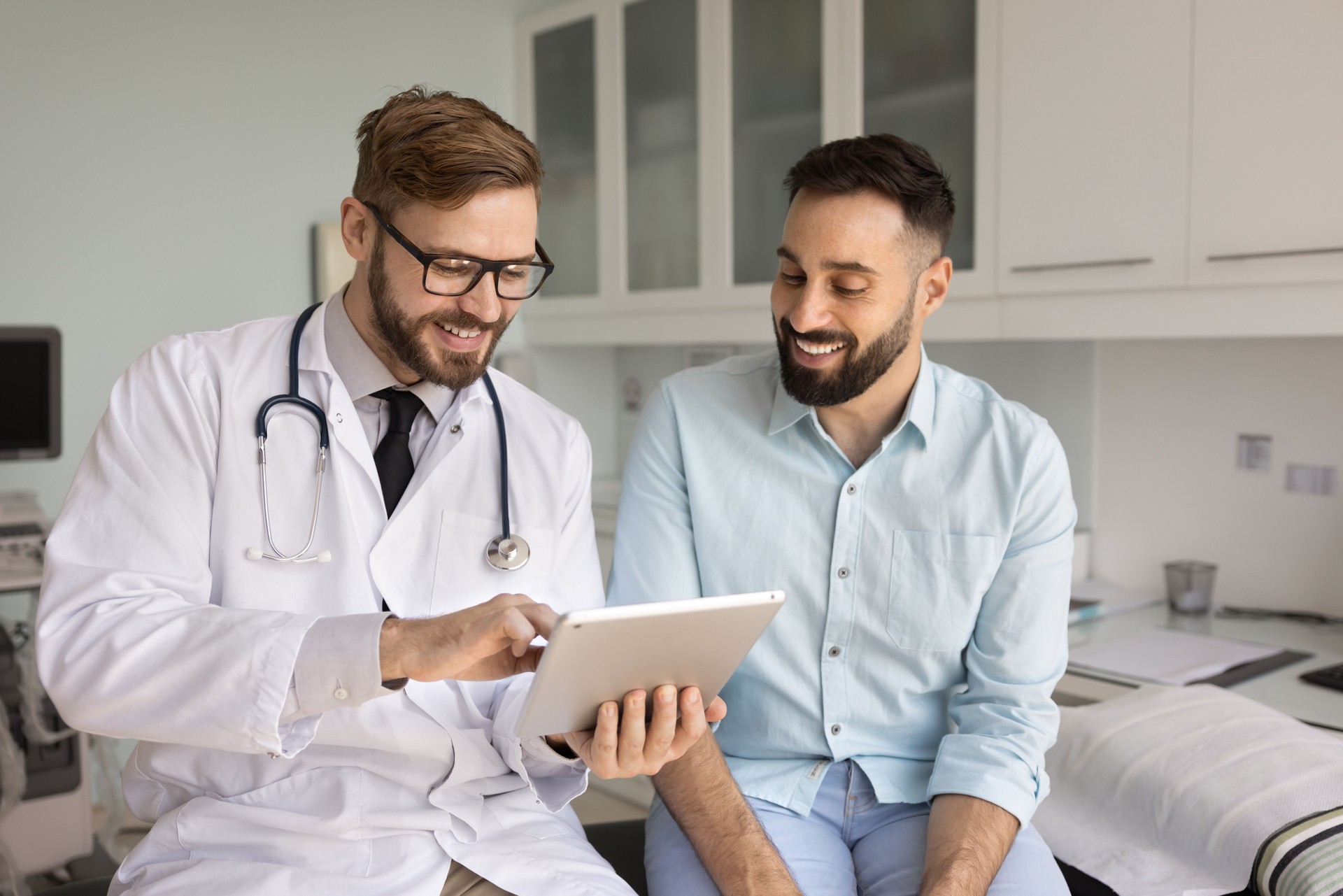 Positive male doctor and patient discussing medical examination electronic results